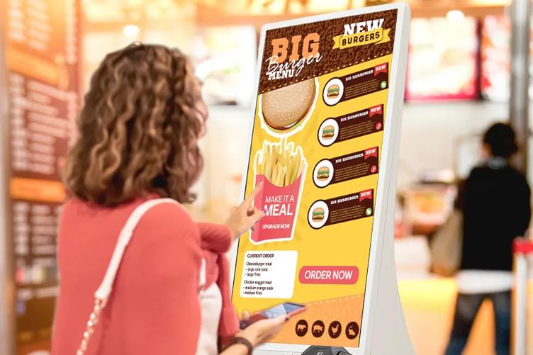 Customer using a self-order kiosk tablet in a restaurant